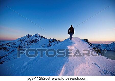 Person hikes along snow covered ridge of Stamsundheia with Steinstind peak in distance, Stamsund, Vestv? goy, Lofoten islands, Norway View Large Photo Image Stock Image - Person hikes along snow covered ridge of Stamsundheia with Steinstind peak in distance, Stamsund, Vestv? goy, Lofoten islands, Norway. Fotosearch