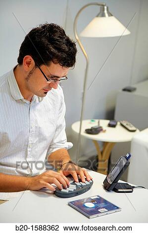 Stock Image - Person labeling a music CD using the braille BlueType keyboard. Fotosearch