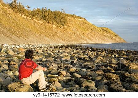 Stock Image - Person on rocky beach - Fort Ebey State Park, Whidbey Island, Washington. Fotosearch