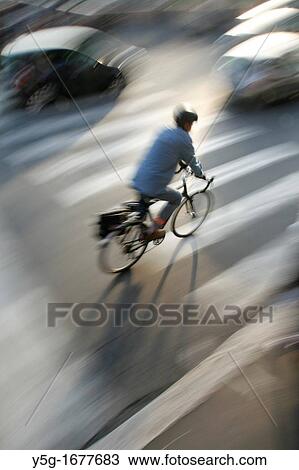 Stock Image - person riding fast bike busy traffic city street in rome italy. Fotosearch
