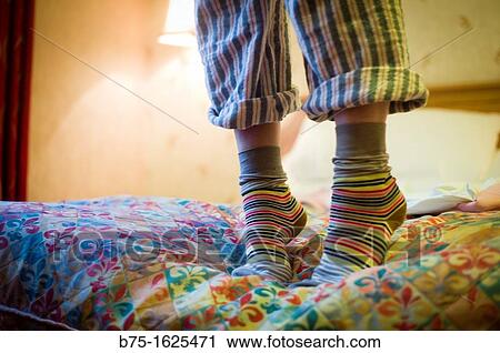 Stock Image - Person standing on bed. Fotosearch