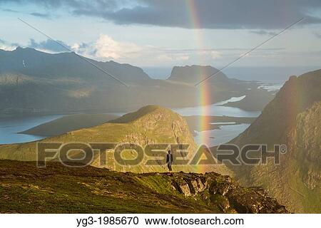 Person stands under rainbow near summit of Ryten, Lofoten Islands, Norway. View Large Photo Image Stock Image - Person stands under rainbow near summit of Ryten, Lofoten Islands, Norway.. Fotosearch