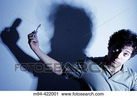 Stock Image - Person trying to talk to his shadow by mobile phone.. Fotosearch