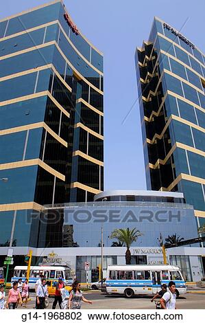 Stock Image - Peru, Lima, Miraflores, Malecon de la Reserva, JW Marriott, five-star hotel, chain, luxury, office tower, building, Arquitectonica, architecture, entrance, glass, design, tour bus, exterior, Hispanic, man, woman, pedestrian,.. Fotosearch