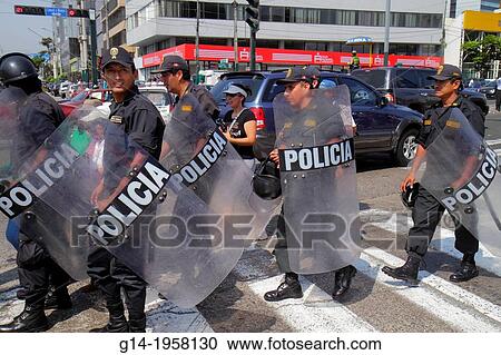 Stock Image - Peru, Lima, San Isidro, Avenida Canaval y Moreyra, protest, Petroperu, Petr? leos del Per, street scene, Indigenous Communities Protest Against Oil Pollution, Hispanic, man, woman, riot police, public order, shield, helmet, formation, crossing,.. Fotosearch