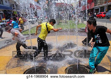 Peru, Tacna, Avenida San Martin, Plaza de Armas, interactive water feature, fountain, water jet, spout, Hispanic, teen, boy, playing, roughhousing, rowdy, getting wet, mischievous,. View Large Photo Image Picture - Peru, Tacna, Avenida San Martin, Plaza de Armas, interactive water feature, fountain, water jet, spout, Hispanic, teen, boy, playing, roughhousing, rowdy, getting wet, mischievous,.. Fotosearch