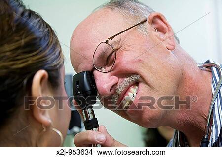 Phoenix, Arizona - The Centro de Salud, or Health Center, at Wesley Community Center Dr Steven Herf uses an ophthalmoscope to examine a patient's eye The Centro de Salud has a bilingual staff and serves primarily persons without insurance It is suppor View Large Photo Image Picture - Phoenix, Arizona - The Centro de Salud, or Health Center, at Wesley Community Center Dr Steven Herf uses an ophthalmoscope to examine a patient's eye The Centro de Salud has a bilingual staff and serves primarily persons without insurance It is suppor. Fotosearch