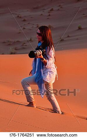 Stock Image - photographer at sunset in the Sahara Desert at Erg Chigaga, Morocco. Fotosearch