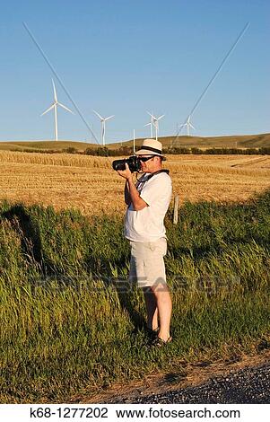Stock Image - Photographer photographing wind turbines near Pincher Creek, Alberta, Canada. Fotosearch