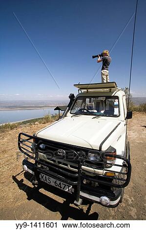 Photographer standing on safari vehicle - Lake Nakuru National Park, Kenya View Large Photo Image Stock Image - Photographer standing on safari vehicle - Lake Nakuru National Park, Kenya. Fotosearch