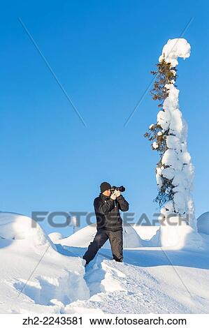 Stock Image - Photographer taking picture of winter landscape.. Fotosearch