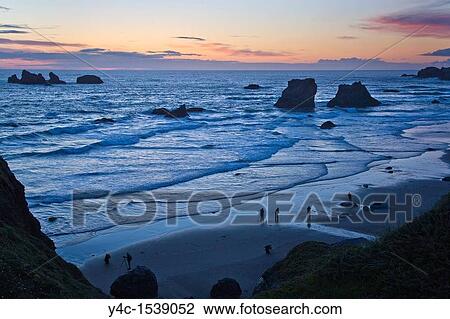 Stock Image - Photographers on Bandon Beach at sunset with seastacks on the Pacific Ocean coast of Bandon Oregon. Fotosearch