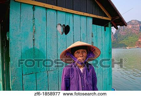 Stock Photo - Picturesque scene old woman in purple in fishing village in Halong Bay Ha Long relax Vietnam. Fotosearch