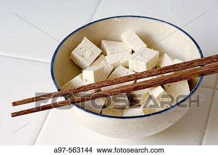 Picture - Pieces of Tofu cut into cubes and sitting in a bowl with a pair of chopsticks resting on top.. Fotosearch
