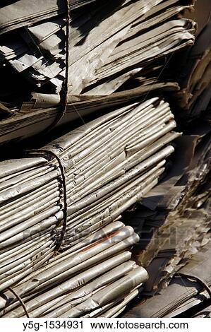 Stock Image - pile of old used newspapers left in street road in city town. Fotosearch