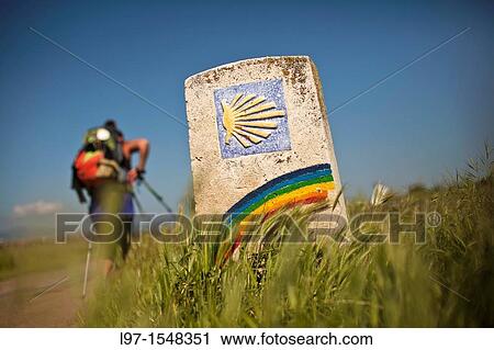 Stock Image - Pilgrim and marker with rainbow along the Camino de Santiago. Fotosearch