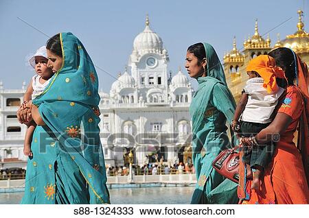 Stock Image - Pilgrims walking around Golden Temple by the holly lake, Punjab Amritsar India. Fotosearch