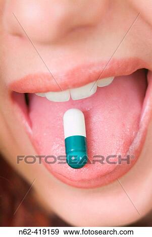 Pillon green and white resting on the tongue of a girl with open mouth View Large Photo Image Stock Photo - Pillon green and white resting on the tongue of a girl with open mouth. Fotosearch