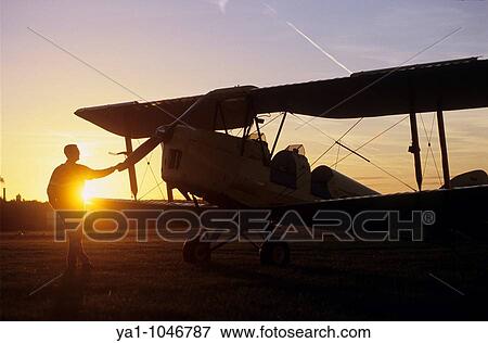 Pilot near an old trainer biplane De Havilland DH 82a Tiger Moth on sunset View Large Photo Image Stock Photo - Pilot near an old trainer biplane De Havilland DH 82a Tiger Moth on sunset. Fotosearch