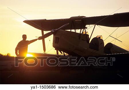 Pilot near an old trainer biplane De Havilland DH 82a Tiger Moth on sunset View Large Photo Image Stock Photograph - Pilot near an old trainer biplane De Havilland DH 82a Tiger Moth on sunset. Fotosearch