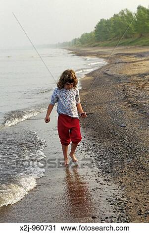 Stock Image - Pinery Provincial Park, Ontario - Mariel West, 6, collects colorful stones as she walks the shore of Lake Huron on a foggy morning MR. Fotosearch