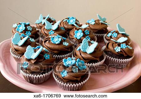 Pink Plate Of Cupcakes With Chocolate Frosting Swirl And Blue