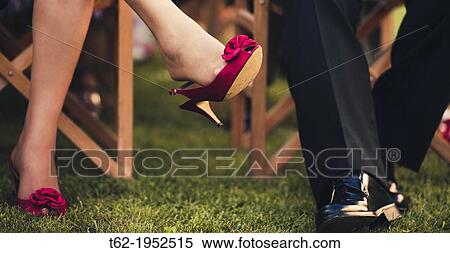 Stock Photography - Plan of the legs of two guests at a wedding during the ceremony.. Fotosearch