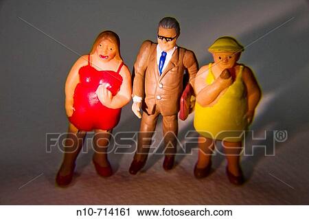 Plastic figures of a man, wearing glasses and holding a satchel, standing between two heavy women. View Large Photo Image Stock Image - Plastic figures of a man, wearing glasses and holding a satchel, standing between two heavy women.. Fotosearch