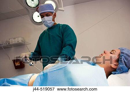 Plastic surgeon during a liposuction procedure to a woman in surgery room. View Large Photo Image Stock Photo - Plastic surgeon during a liposuction procedure to a woman in surgery room.. Fotosearch