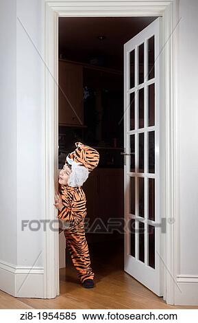Stock Photography - Playful child dressed in tiger costume, plays hide and seek.. Fotosearch