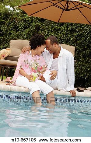 Playful couple laughing poolside View Large Photo Image Stock Photograph - Playful couple laughing poolside. Fotosearch
