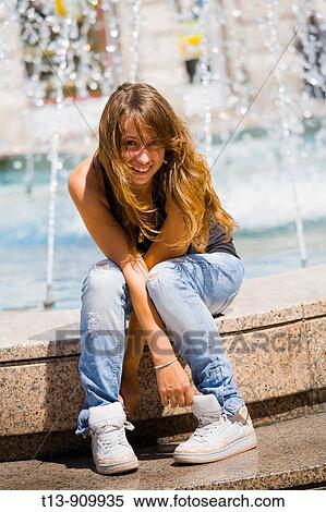 Stock Photography - Playful young woman on fountain. Fotosearch
