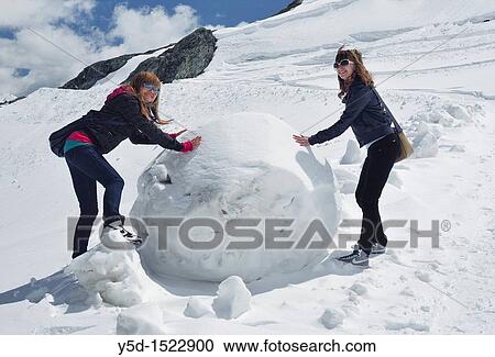 Stock Image - playing with a big snow ball in Swiss Alps, canton Valais, Switzerland. Fotosearch