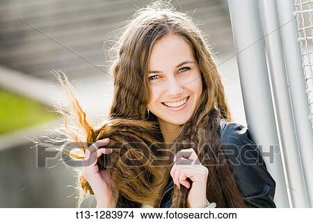 Picture - Playing with her long hair happy young woman. Fotosearch