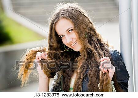 Stock Photography - Playing with her long hair happy young woman. Fotosearch