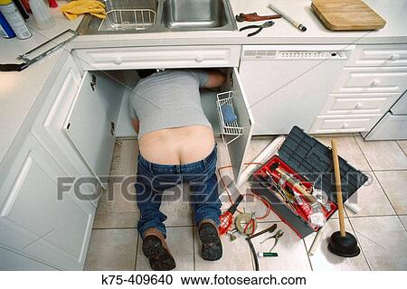 Plumber under kitchen sink View Large Photo Image Stock Image - Plumber under kitchen sink. Fotosearch