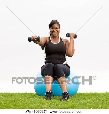 Plus size model working out with weights on cardio ball View Large Photo Image Picture - Plus size model working out with weights on cardio ball. Fotosearch