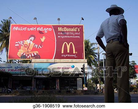 Stock Photo - Policeman standing in front of McDonald's commercial sign, Mysore, India. Fotosearch
