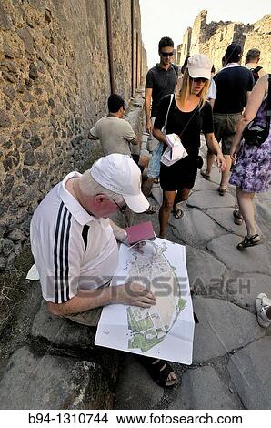 Pompeii, Roman ruins. Tourist consulting a map. Roman town buried in AD 79 by ash flows from Vesuvius volcano. UNESCO world heritage site. Province of Naples in Campania. Italy. View Large Photo Image Picture - Pompeii, Roman ruins. Tourist consulting a map. Roman town buried in AD 79 by ash flows from Vesuvius volcano. UNESCO world heritage site. Province of Naples in Campania. Italy.. Fotosearch