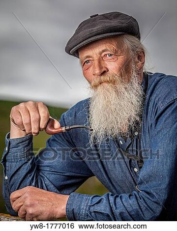 Stock Photograph - Portait of senior man with beard smoking a pipe. Fotosearch