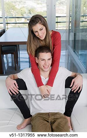 Stock Photography - Portrait if a sweet couple sitting on the sofa. Fotosearch