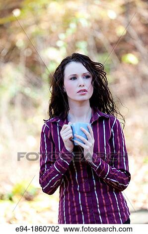 Portrait of 24 year old brunette woman holding a coffee cup in a back yard in the fall View Large Photo Image Stock Image - Portrait of 24 year old brunette woman holding a coffee cup in a back yard in the fall. Fotosearch