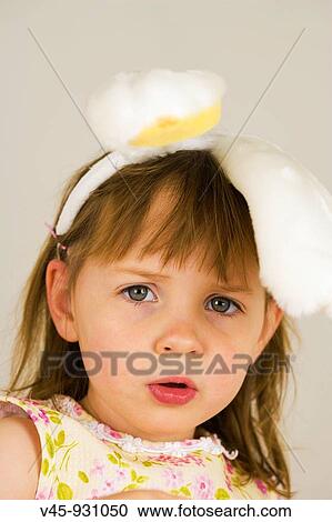 Stock Image - Portrait of 3 year old girl with bunny ears. Fotosearch
