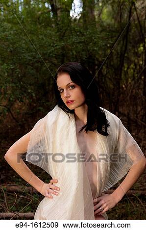 Stock Photo - Portrait of a 20 year old brunettte woman wrapped in white fabric in a forest setting. Fotosearch
