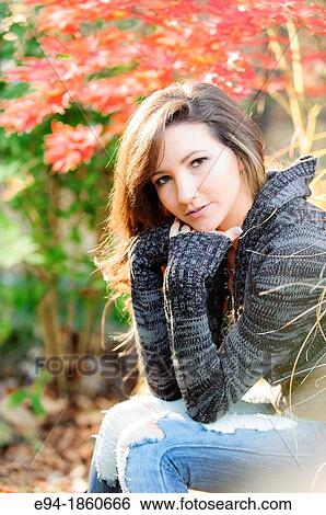 Stock Photograph - Portrait of a 21 year old woman in a garden setting in the fall. Fotosearch