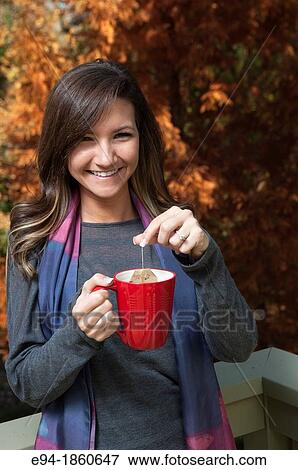 Portrait of a 21 year old woman outdoors holding a cup of tea View Large Photo Image Stock Photo - Portrait of a 21 year old woman outdoors holding a cup of tea. Fotosearch