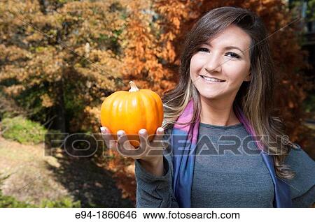 Portrait of a 21 year old woman outdoors holding a small pumpkin View Large Photo Image Stock Photograph - Portrait of a 21 year old woman outdoors holding a small pumpkin. Fotosearch