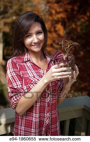 Portrait of a 21 year old woman outdoors holding a jar with a coleus cutting View Large Photo Image Stock Photography - Portrait of a 21 year old woman outdoors holding a jar with a coleus cutting. Fotosearch