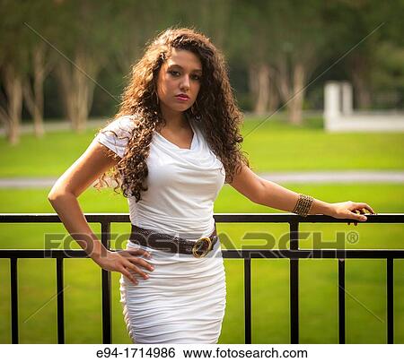 Portrait of a 21 year old woman with long cury black hair wearing a tight white dress in a park View Large Photo Image Stock Photograph - Portrait of a 21 year old woman with long cury black hair wearing a tight white dress in a park. Fotosearch