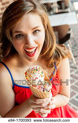 Stock Image - Portrait of a 22 year old brunette woman outdoors with an ice cream cone. Fotosearch